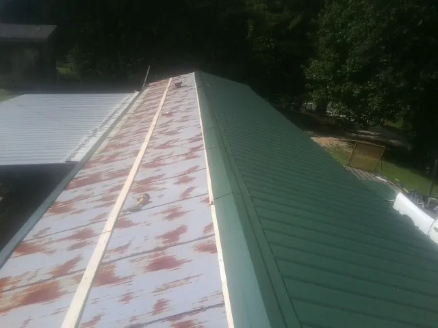 Old rusted panels beside newly installed green metal roofing — Wind Damage Roof Repair by Roofing Brothers in Aspinwall