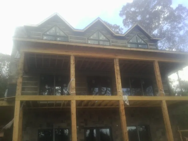 Dormers and porch framing on a large log home under construction — Roof Coating work by our crew in Aspinwall