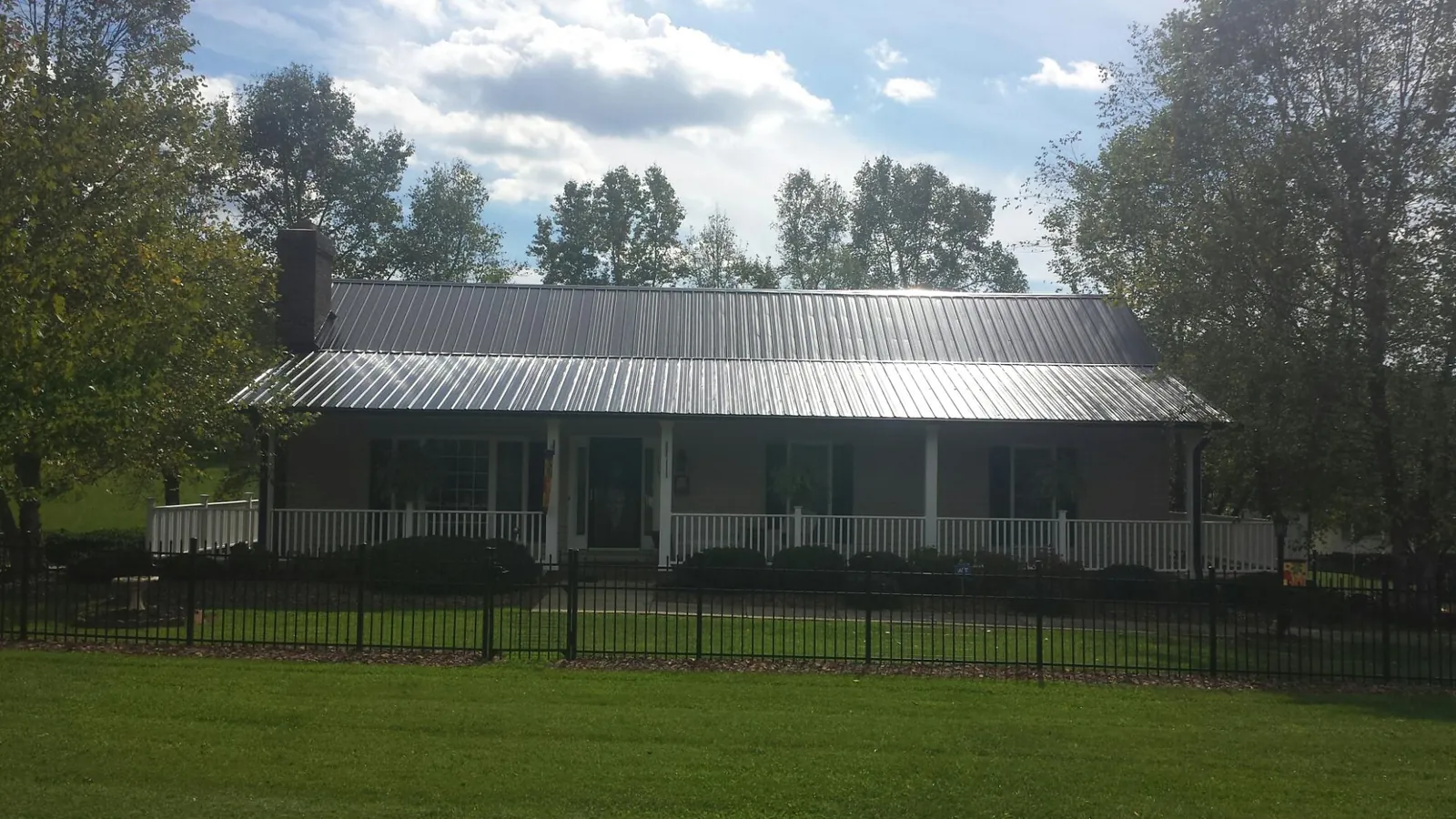 Gray metal roof on a brick ranch with a full width front porch — Gutter Guard Installation work by our crew in Aspinwall