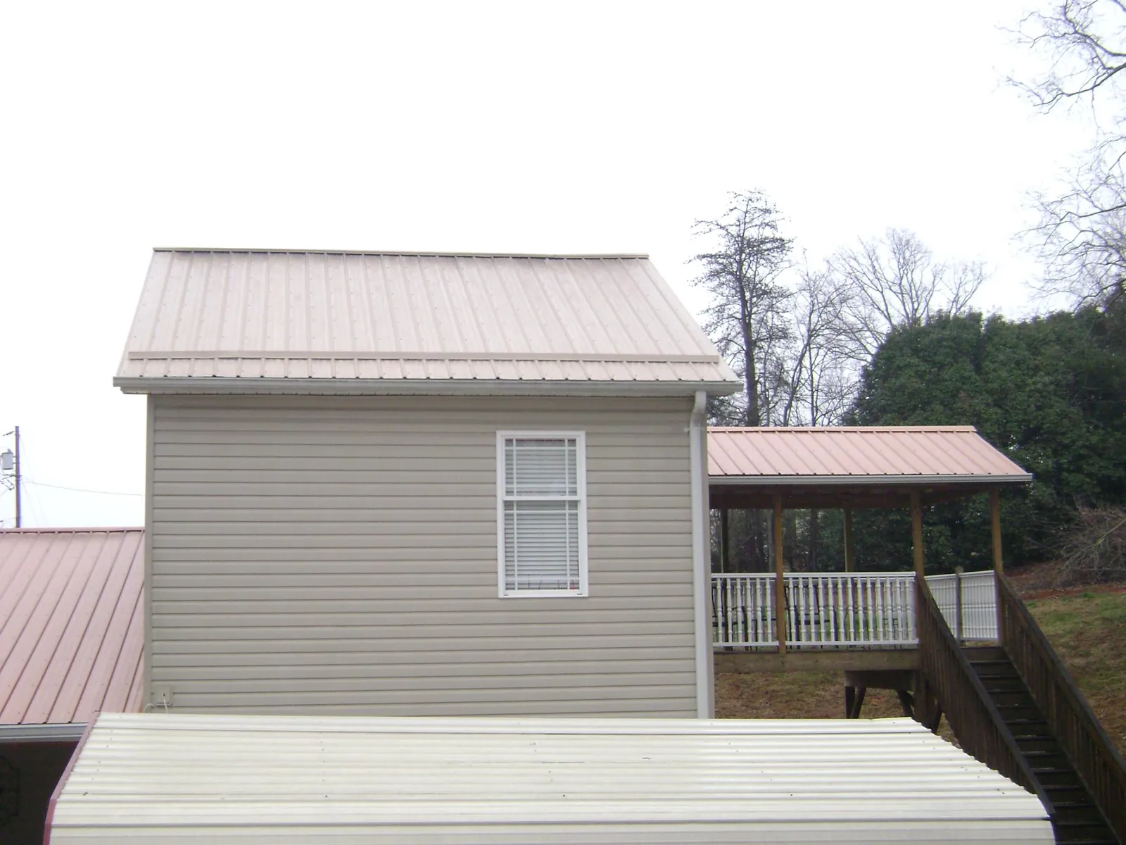Tan metal roofs on a two story addition and attached porch, from a Roof Replacement job in Aspinwall