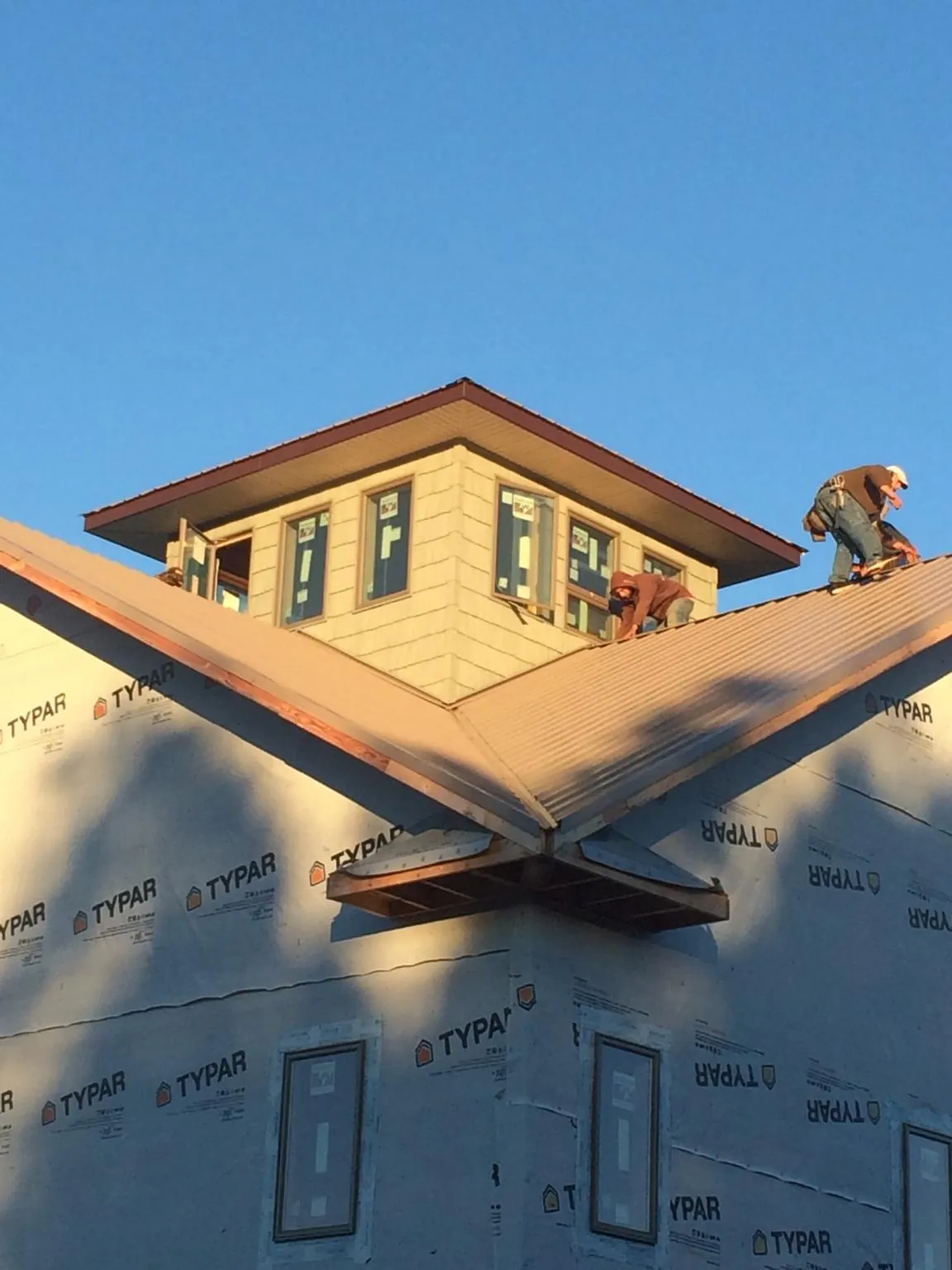 Roofers working around a rooftop cupola on a new metal roof at sunset — Roof Waterproofing in Aspinwall by Roofing Brothers